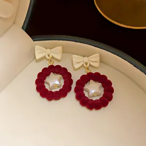 Detail showing red velvet ring earrings with white bow and star inside a jewelry box