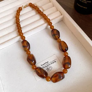 Close-up of Maillard style acrylic irregular bead necklace in warm amber tones.