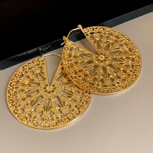 Vue détaillée du motif géométrique évidé sur ces boucles d'oreilles vintage en métal doré.
