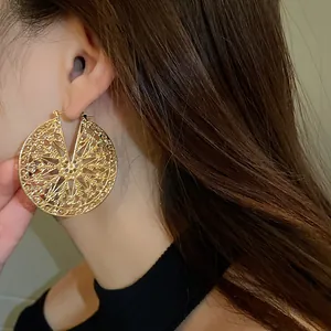 Vue détaillée montrant le motif filigrane doré complexe sur une boucle d'oreille.