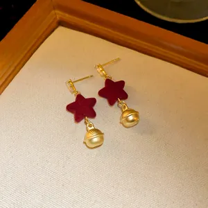 Detail of wine red velvet star earrings with golden matte finish bells