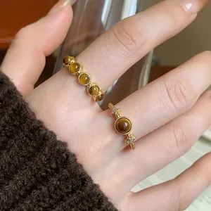 Close-up shot of retro gold-plated tiger eye rings with Maillard style worn on a hand