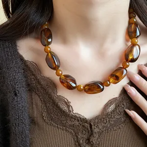 Close-up detail of retro amber acrylic beaded necklace with irregular shapes on model neck