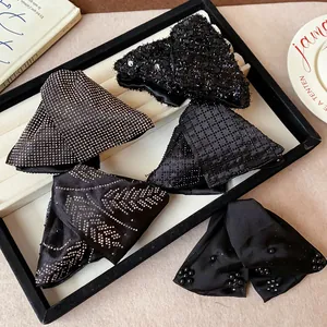 Close-up detail of five black fabric triangle hair clips with sequins and rhinestones.