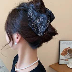 Close-up of black fabric bow hair claw clip with sparkling rhinestone details for women