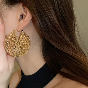 Gros plan détaillé de boucles d'oreilles créoles dorées en filigrane sur un mannequin