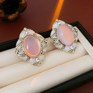 Close-up of vintage palace style floral stud earrings with pink oval stones and gold frame