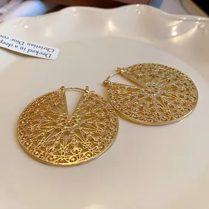 Détail macro de boucles d'oreilles créoles dorées filigranes vintage sur un plateau