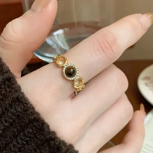 Exquisite close-up of retro gold-plated tiger eye ring with crystal halo on finger.