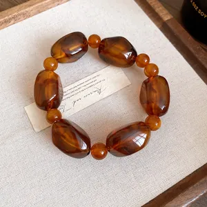 Close-up of a vintage amber acrylic beaded necklace on a linen background.