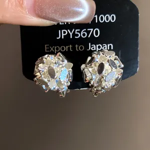 Detailed view of silver-toned flower cluster clip-on earrings on black display card packaging