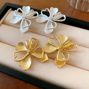 Detalle de primer plano de los pendientes de flor retro dorados y blancos en un joyero