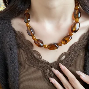 Close-up of vintage amber acrylic beaded necklace on model with brown lace top