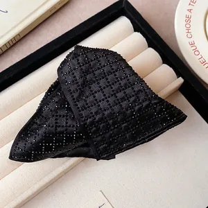Close-up detail of a large black fabric triangle hair claw clip with rhinestone grid pattern.