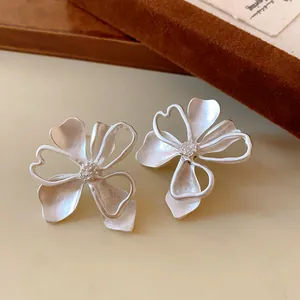 Detalle de pendientes de flores vintage plateados con pétalos calados.