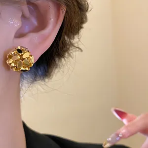 Detailed macro view of a luxury 18k gold-plated flower cluster ear clip on a model's ear