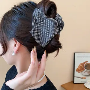 Detailed view of a large black rhinestone bow hair claw clip styled in an elegant updo