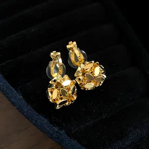 Macro view of detailed 18k gold plated flower cluster clip-on earrings on black velvet tray