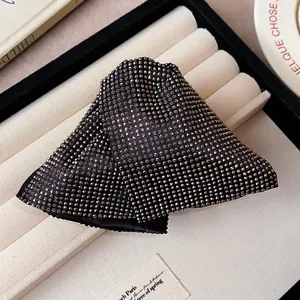Detailed view of a black fabric triangular hair claw clip covered in sparkling rhinestones