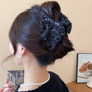 Detailed view of a large black sequined fabric bow hair claw clip styled on a bun.