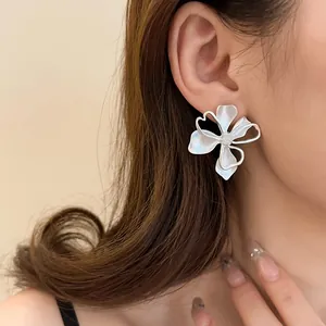 Modelo con pendientes grandes de flores plateadas con pétalos huecos artísticos