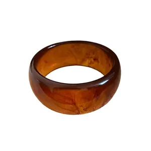 Elegant amber tortoiseshell resin bangle with marbled pattern on a white background