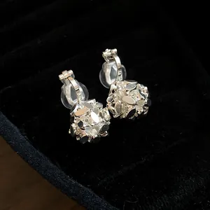 Close-up macro view of silver flower cluster clip-on earrings on black velvet jewelry tray
