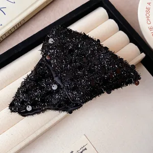 Close-up detail of a elegant black sequined triangular shark hair clip on jewelry display