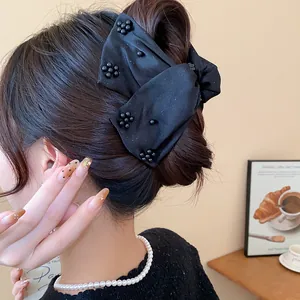 Detailed view of a large black fabric bow hair claw clip with elegant bead accents