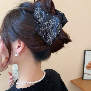 Elegant black fabric bow hair claw clip with rhinestones shown on model hair