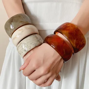 Detailed macro view of stylish marble resin bangles worn on a woman's wrists, chic accessory