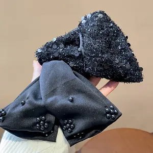 Detail shot showing the shimmering sequin texture of the black shark clip and beaded bow.