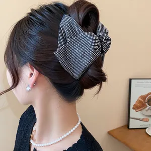 Detail of a large black bow hair claw clip with rhinestones worn in a hair bun