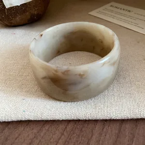 Detailed view of a wide resin bangle with a brown marble-patterned finish on canvas