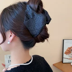 Elegant large black fabric bow hair claw clip shown in detail on an Asian model