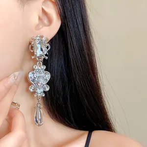 Detailed macro view of an ornate silver long drop earring with square and teardrop crystals