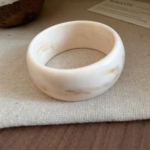 Close-up of a marbled off-white resin bangle bracelet on a linen surface
