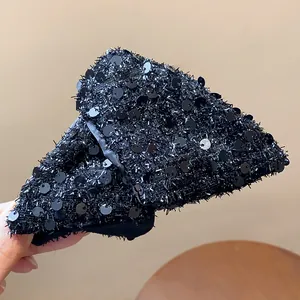 Close-up of black sequin-covered triangle hair claw clip with shaggy texture details.