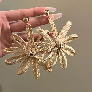 Vue détaillée des boucles d'oreilles en paille de raphia tissée à la main en main