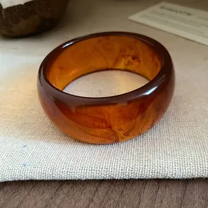 Macro detail of an amber resin bangle with elegant marbled swirls and smooth glossy finish.