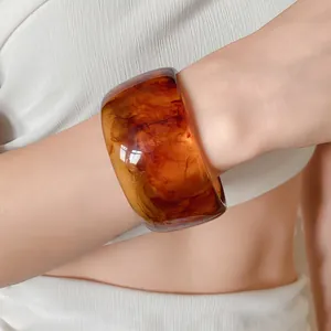Close-up detail of a thick amber resin bangle with unique marbled swirl pattern on a wrist