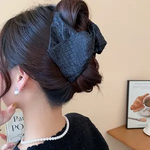 Elegant large black fabric bow hair claw clip styled on a brunette's updo hairstyle