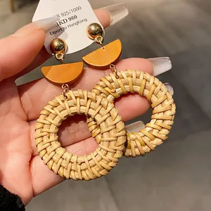 Vue détaillée de boucles d'oreilles bohèmes en raphia tressé avec des clous d'oreilles dorés