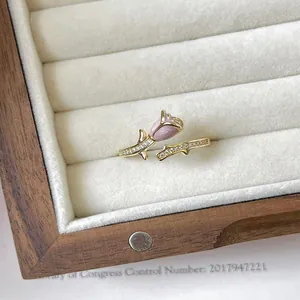 Primo piano di un elegante anello a rosa dorata con bocciolo rosa e cristalli.