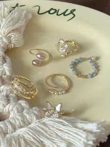 Eleganti anelli in stile coreano con motivi a fiori, farfalle e perle in finitura dorata.