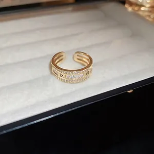 Dettaglio di un anello placcato in oro con numeri romani e zirconi brillanti.