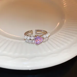 Dettaglio di un elegante anello regolabile con zircone a cuore viola e perle bianche.