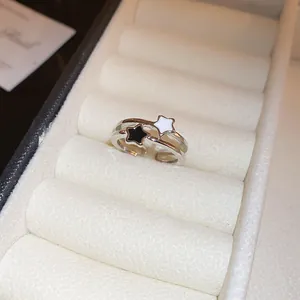 Dettaglio di un anello aperto in argento con decorazioni a stella bianche e nere