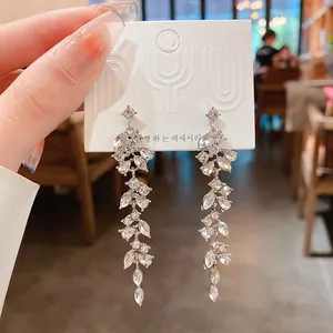 Macro detail of elegant silver-needle leaf tassel earrings with sparkling rhinestones