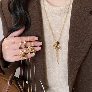 Tiger eye stone rocking horse necklace with zircon details worn on a brown sweater